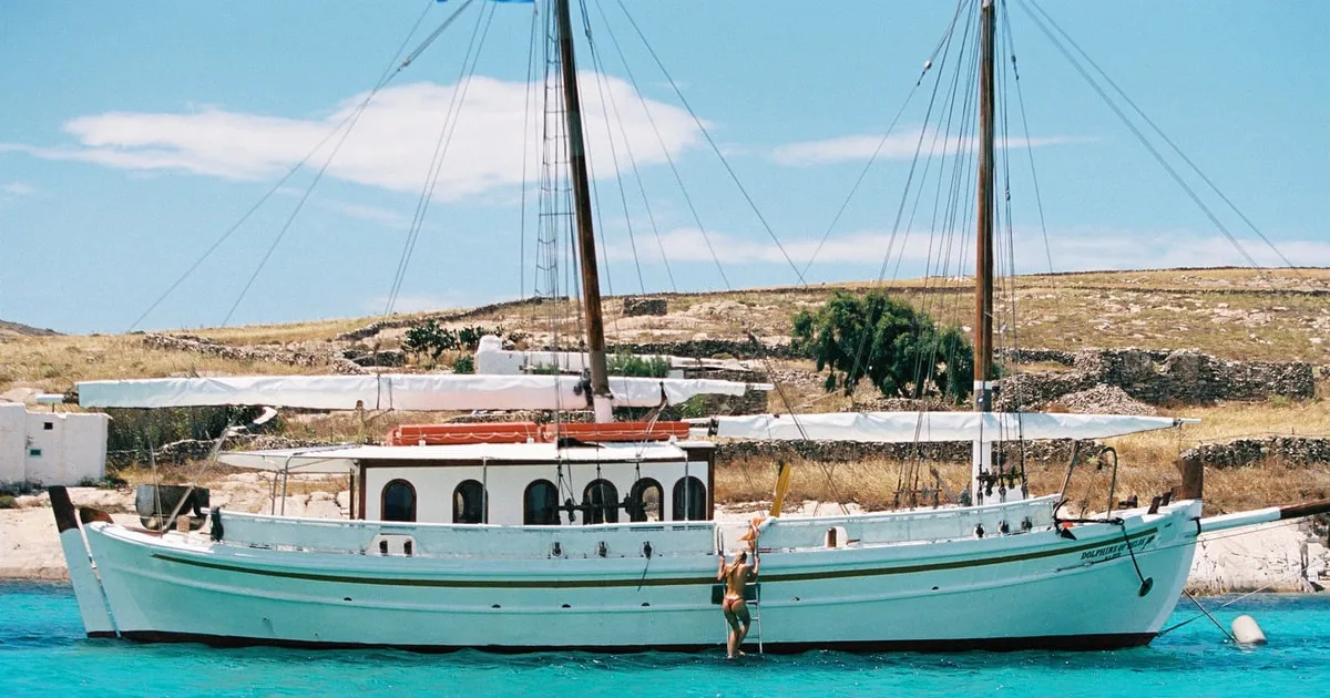 Classic wooden cruise boat anchored in a green cove on Corfu's northeast coast during a full-day Corfu boat tour with lunch