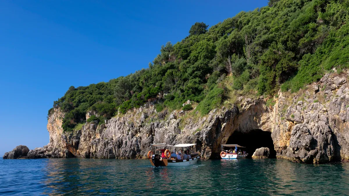 Small boats at the mouth of a sea cave at Paleokastritsa on a Corfu boat tour of the blue caves